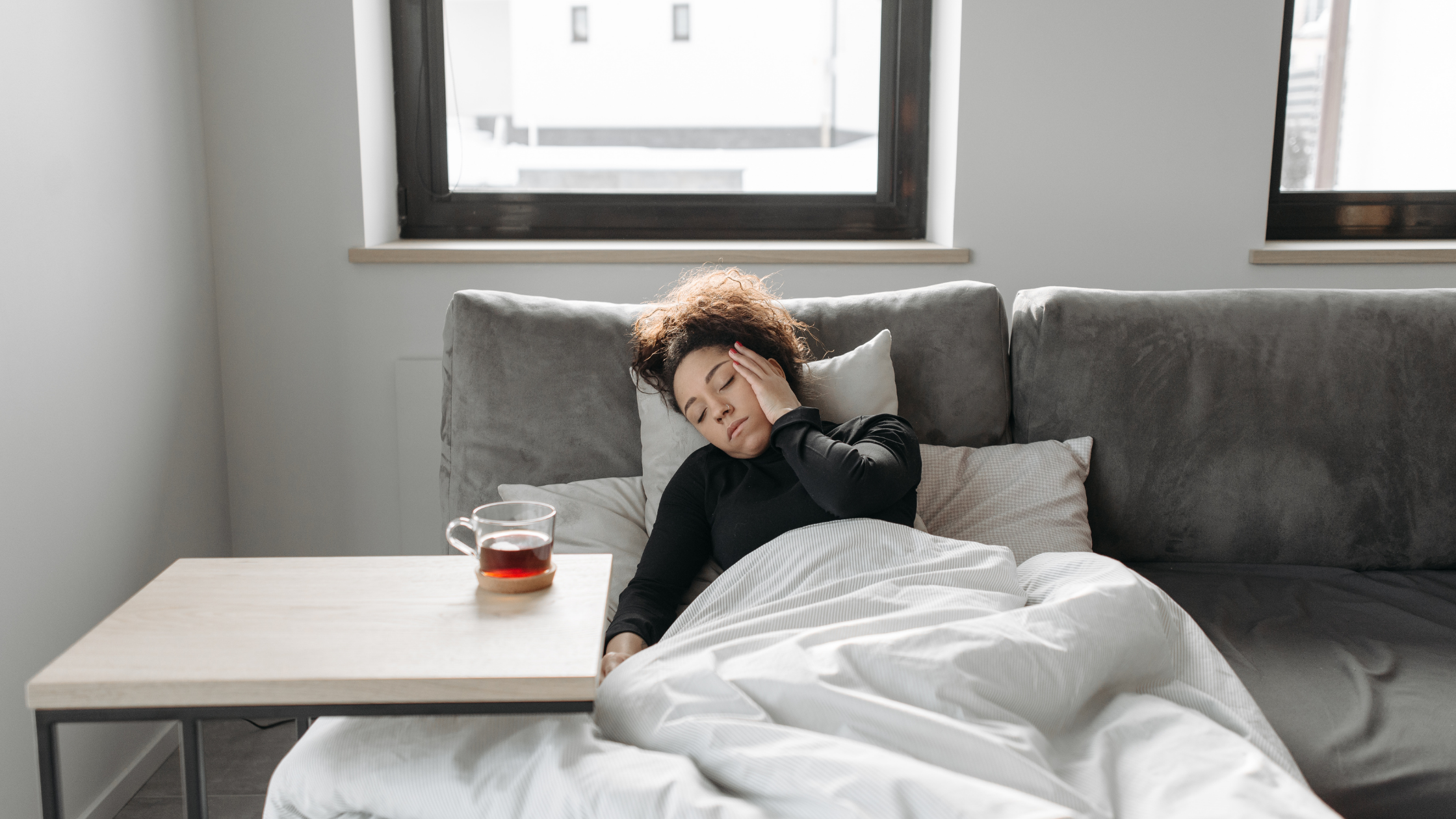 Woman in discomfort from RA flare-up is lying down with a cup of tea Woman in discomfort from RA flare-up is lying down with a cup of tea