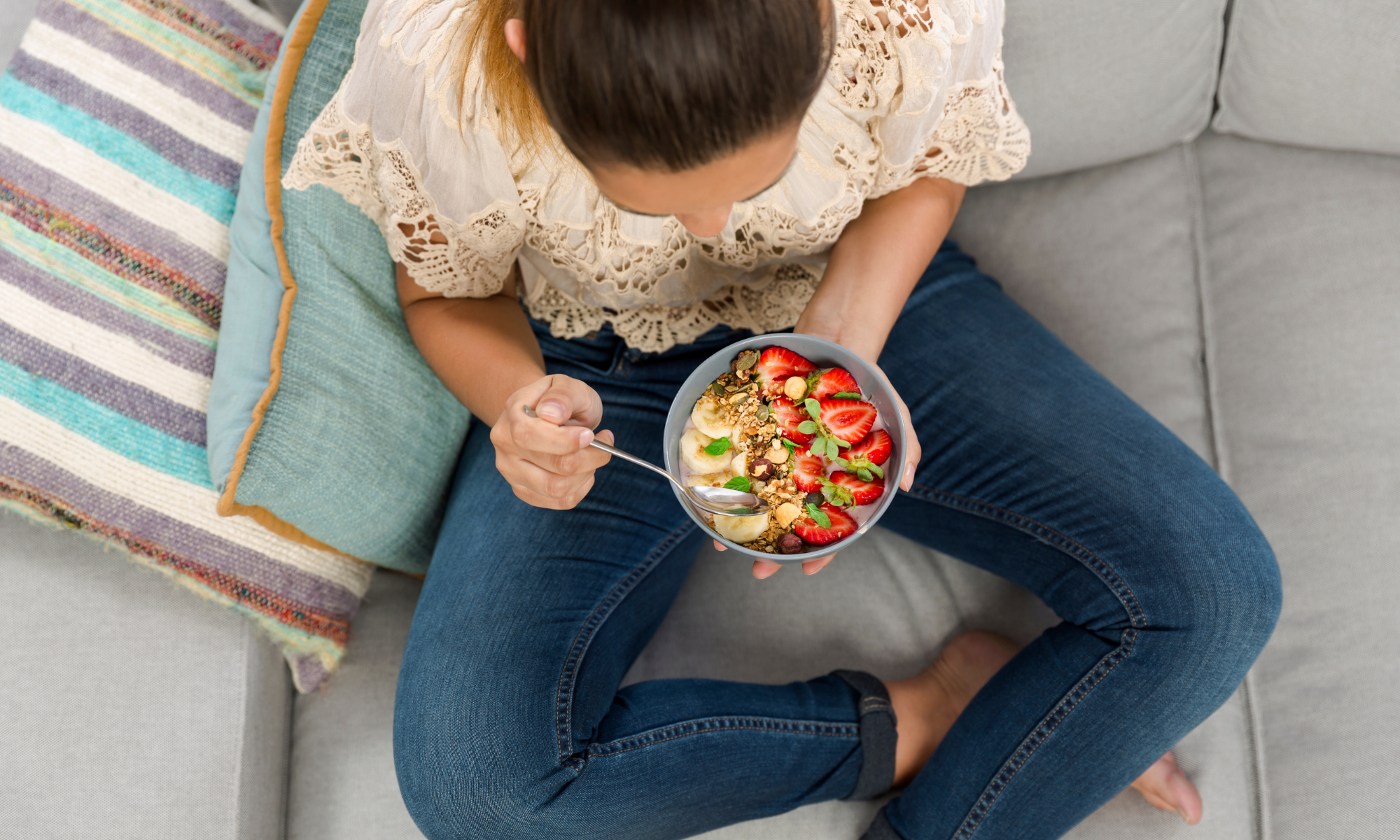 Woman on couch eating a bowl of various fruits and nuts Woman on couch eating a bowl of various fruits and nuts