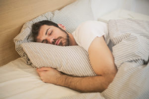 Man hugging pillow and sleeping peacefully