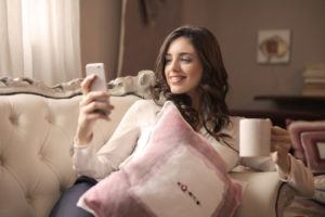 Smiling woman on the couch checks her texts