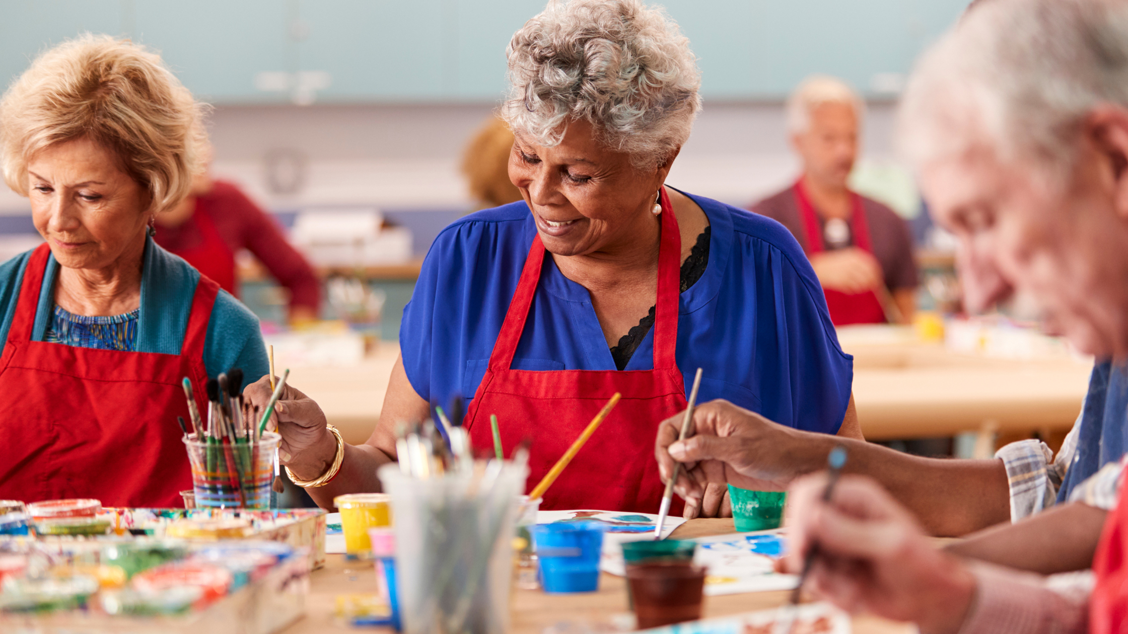 seniors in red aprons taking a painting class seniors in red aprons taking a painting class