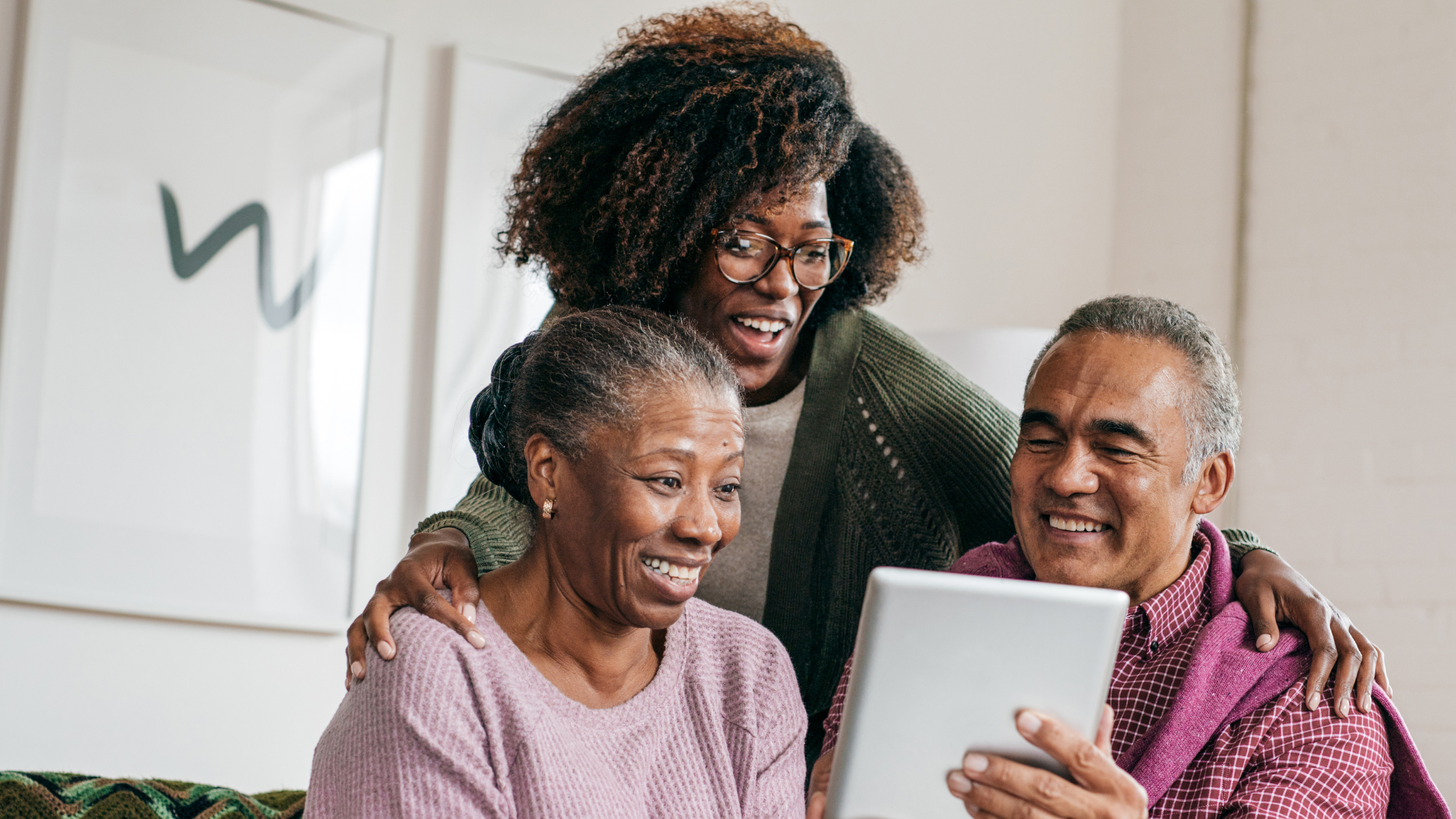 senior couple looking at an iPad with their adult daughter, smiling senior couple looking at an iPad with their adult daughter, smiling