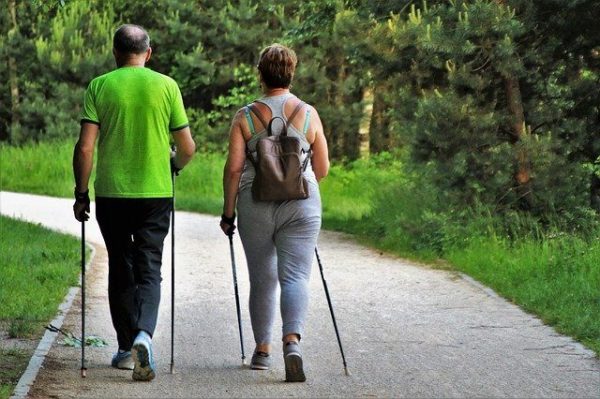 Couple walks on a trail with hiking sticks